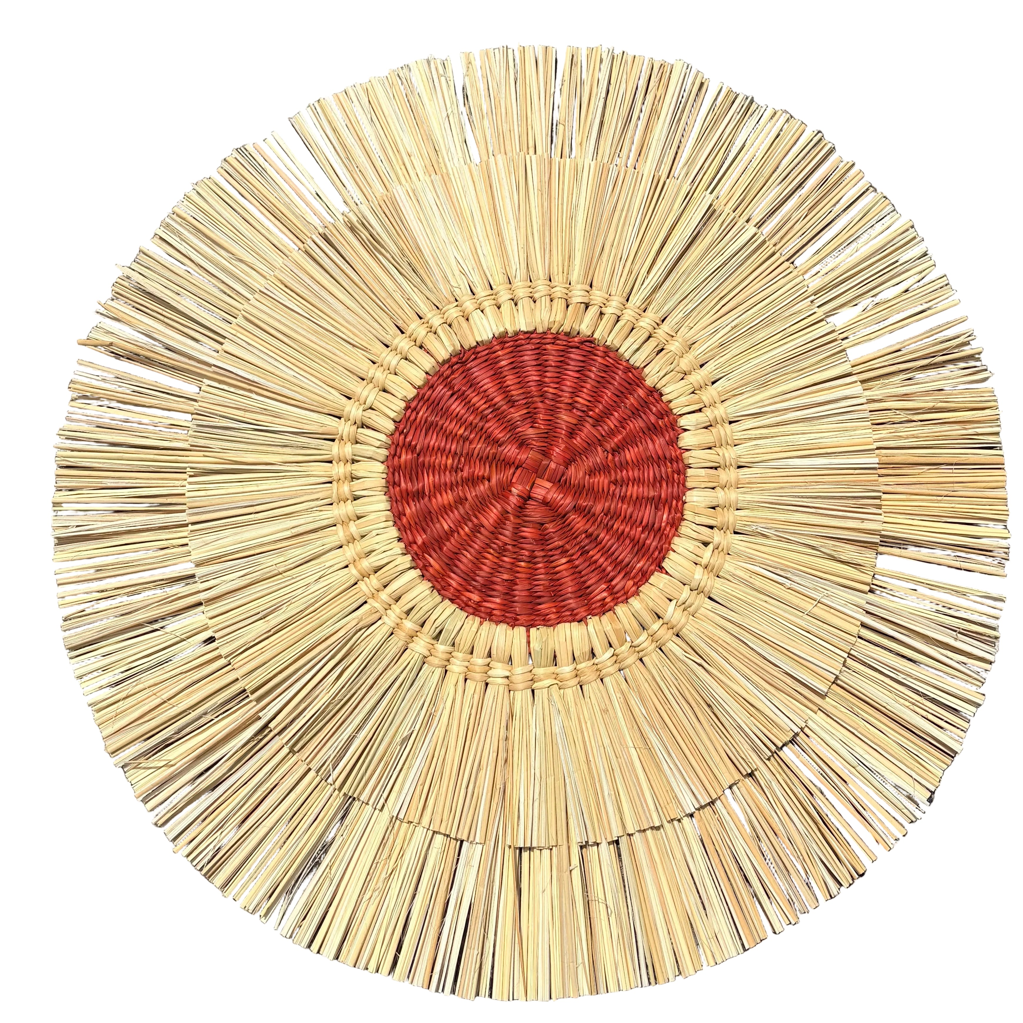 Round woven mat with beige rim and red center on a dark surface