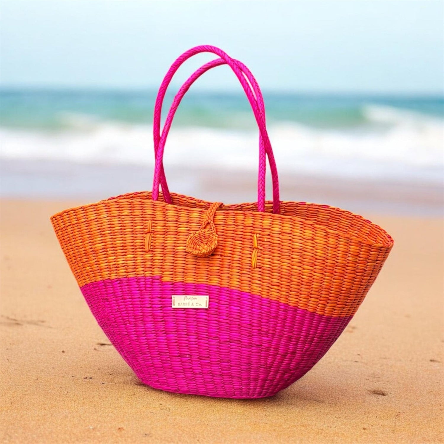 Woven bag with pink top and orange bottom on a beach